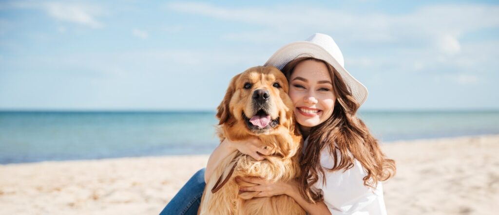mujer feliz con perro golden en la playa